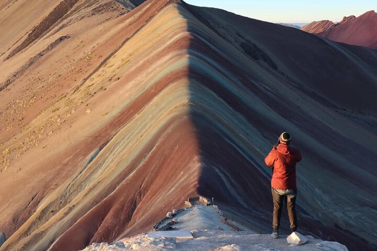 un uomo in piedi accanto a una montagna con un arcobaleno