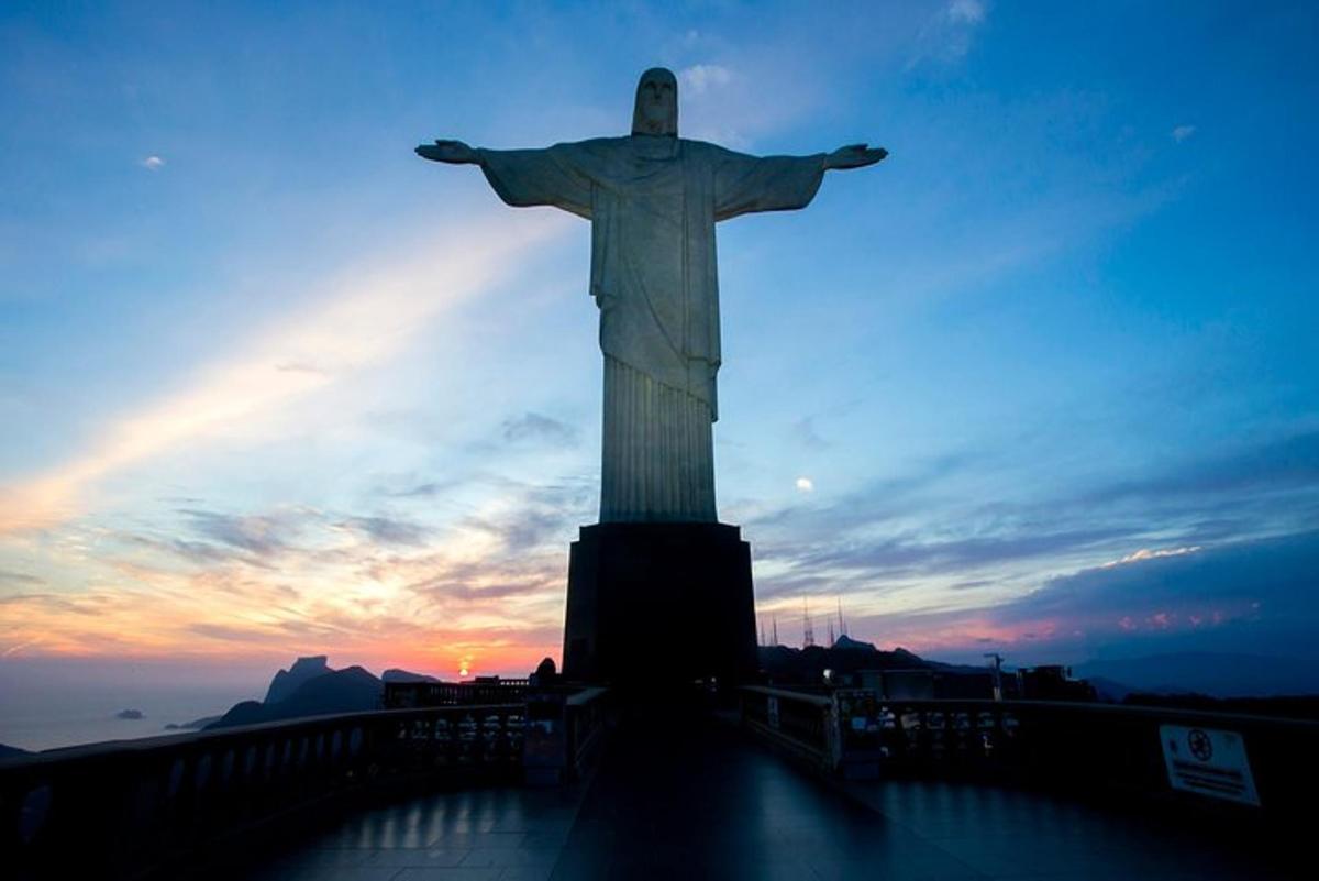 a statue of christ the redeemer at sunset