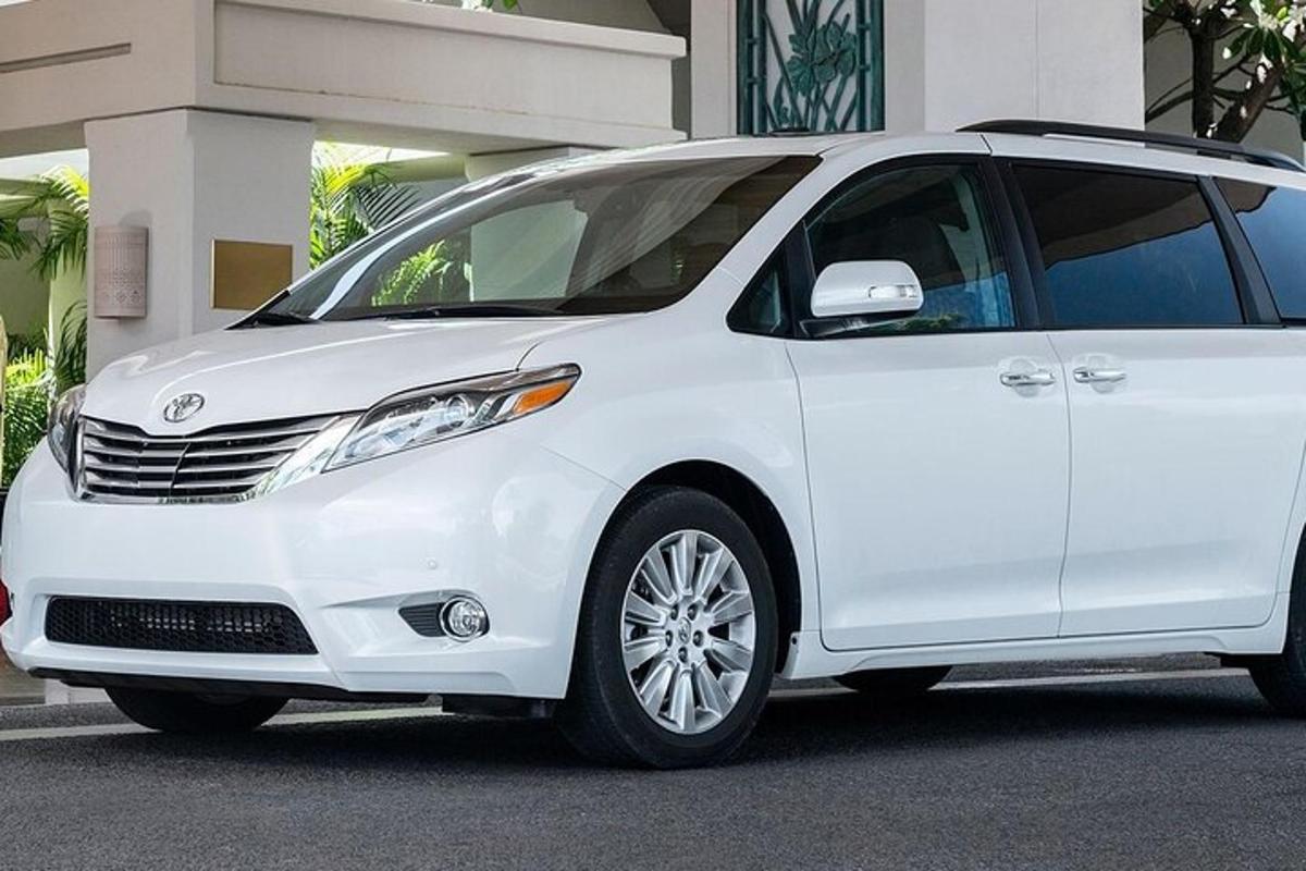 uma minivan branca estacionada em frente a um prédio