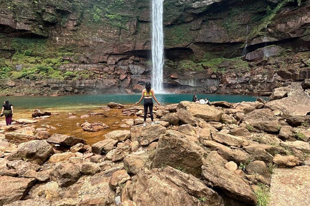 a woman standing on rocks in front of a waterfall