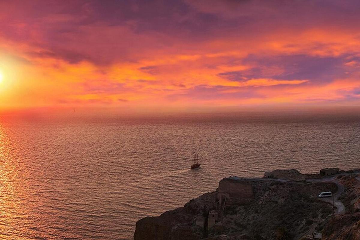um pôr do sol sobre o oceano com um barco na água