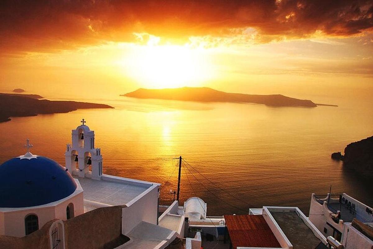 Una puesta de sol sobre el océano con una iglesia y un edificio.