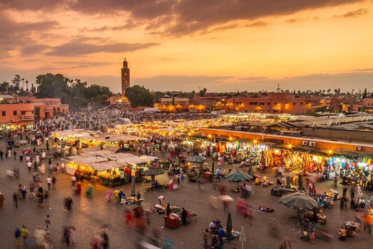uma multidão de pessoas caminhando ao redor de um mercado ao pôr do sol