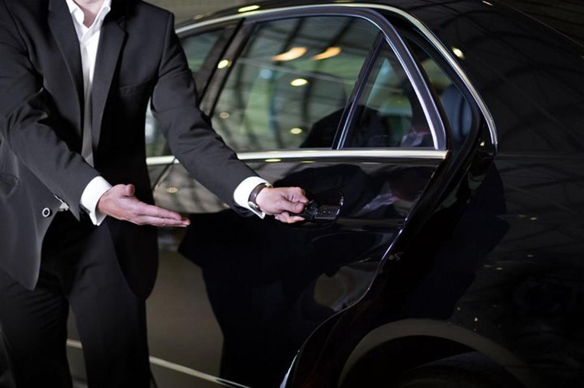 um homem de terno parado ao lado de um carro