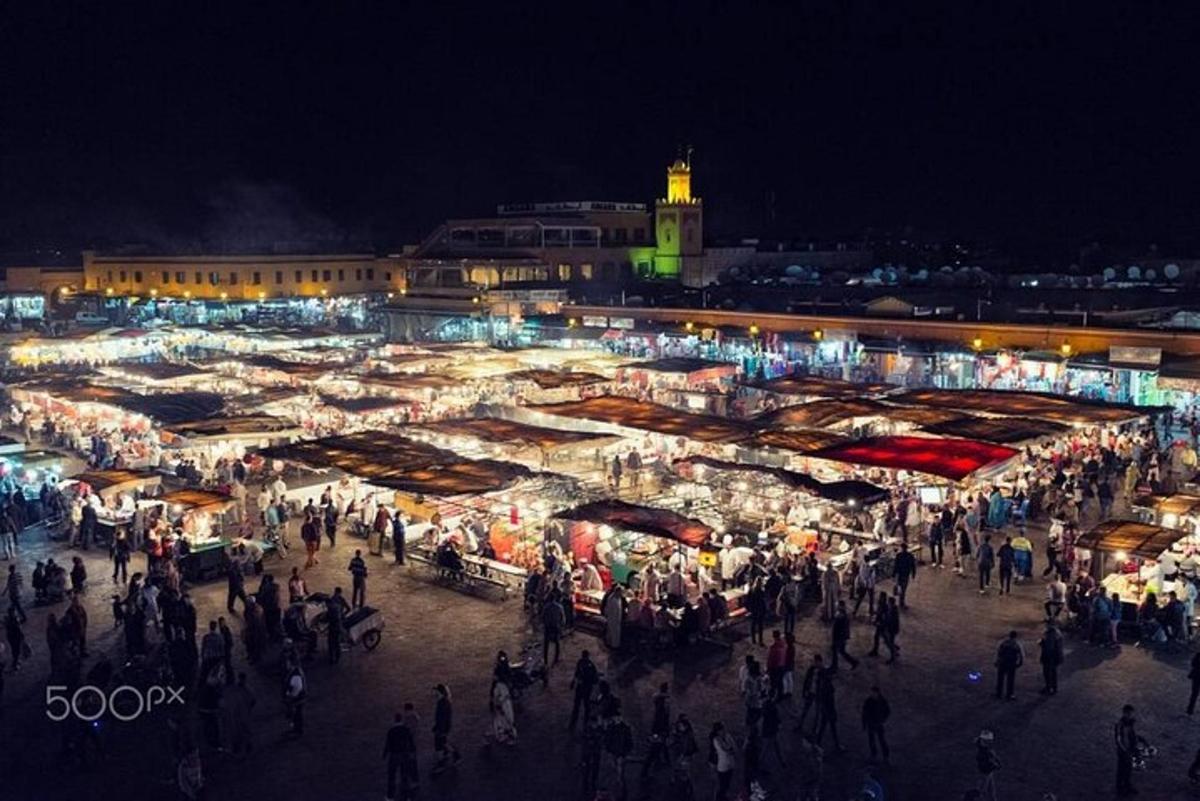 una folla di persone che camminano intorno a un mercato di notte