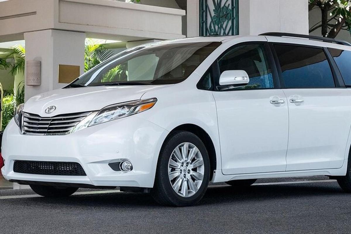 sebuah minivan berwarna putih diletakkan di hadapan sebuah bangunan