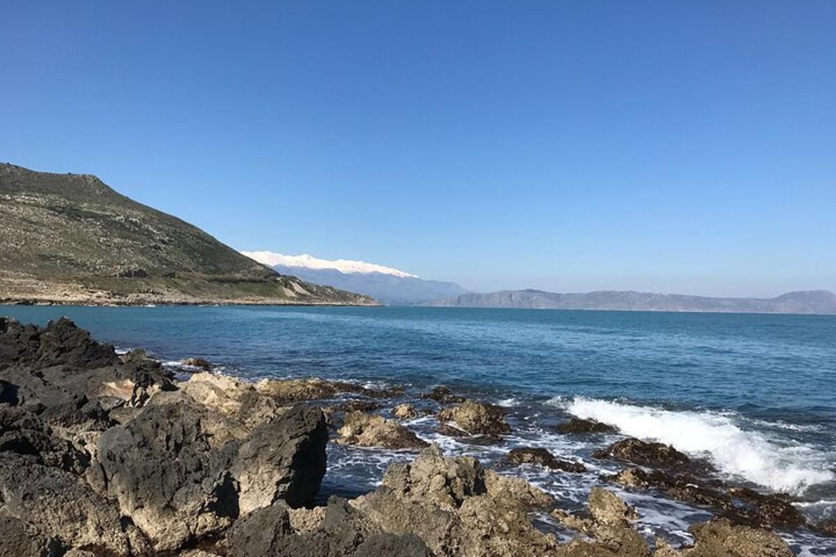a body of water with rocks and mountains in the background