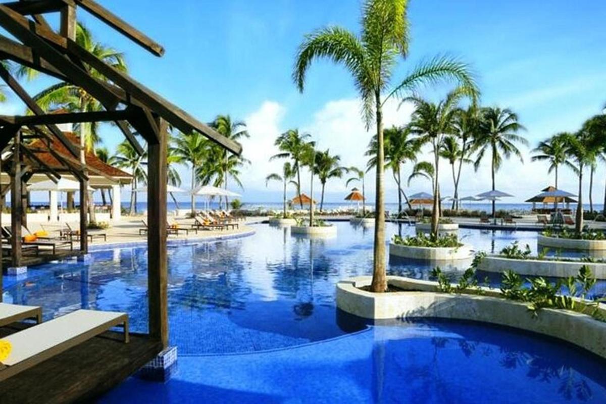 una piscina del resort con palme e l'oceano