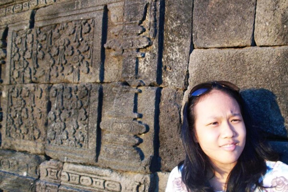 seorang wanita berdiri di hadapan dinding batu