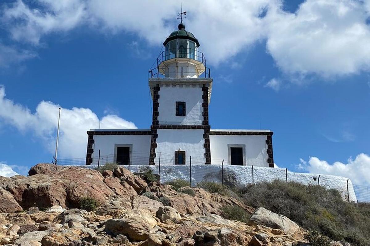 un faro situado en lo alto de una colina rocosa