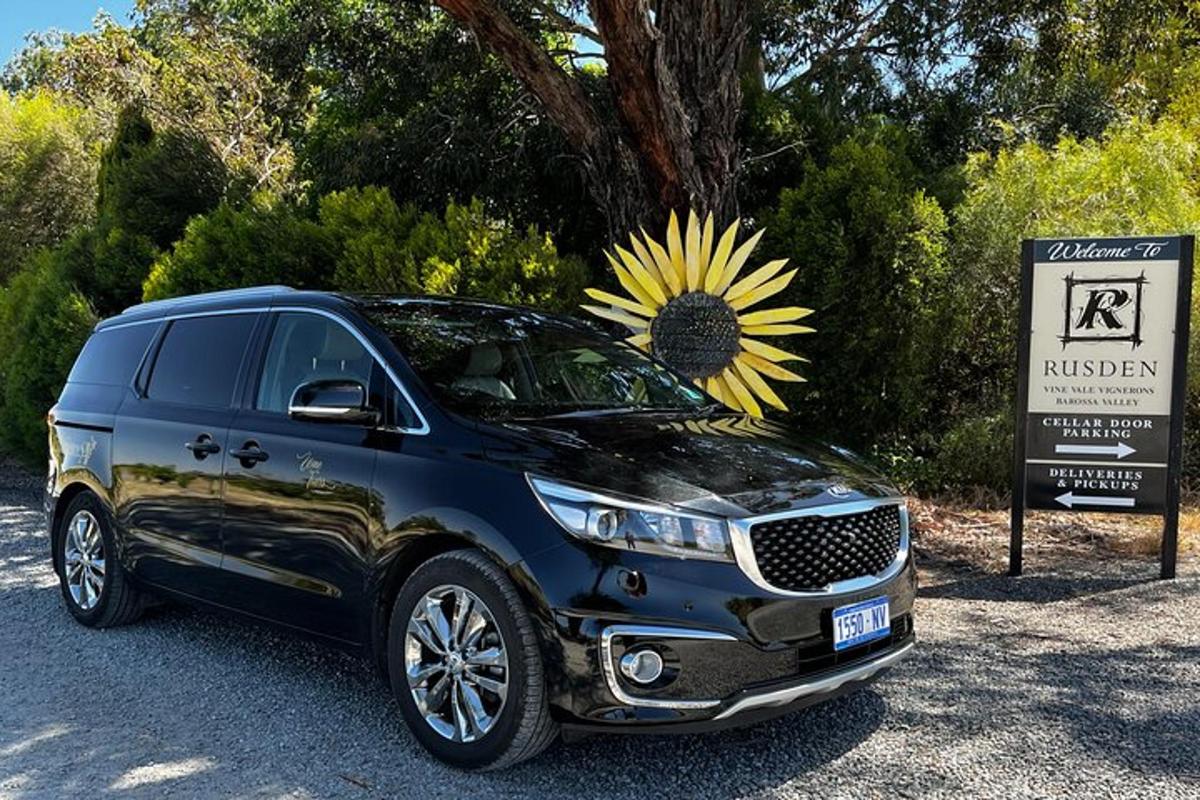 Ένα μπλε SUV παρκαρισμένο δίπλα σε μια πινακίδα με ένα ηλιοτρόπιο στο παρμπρίζ του