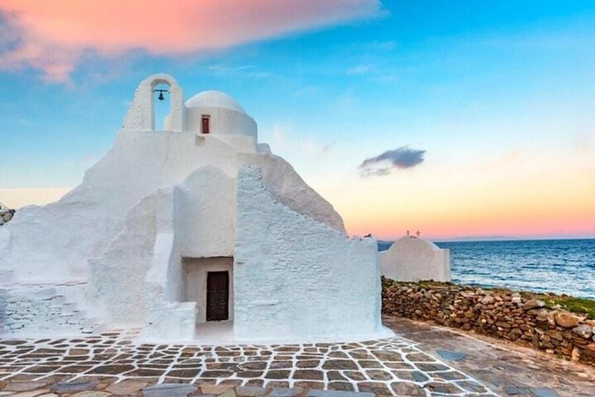 uma pequena igreja branca à beira-mar ao pôr do sol