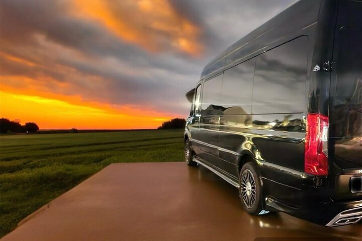 Una camioneta negra estacionada junto a un campo con una puesta de sol