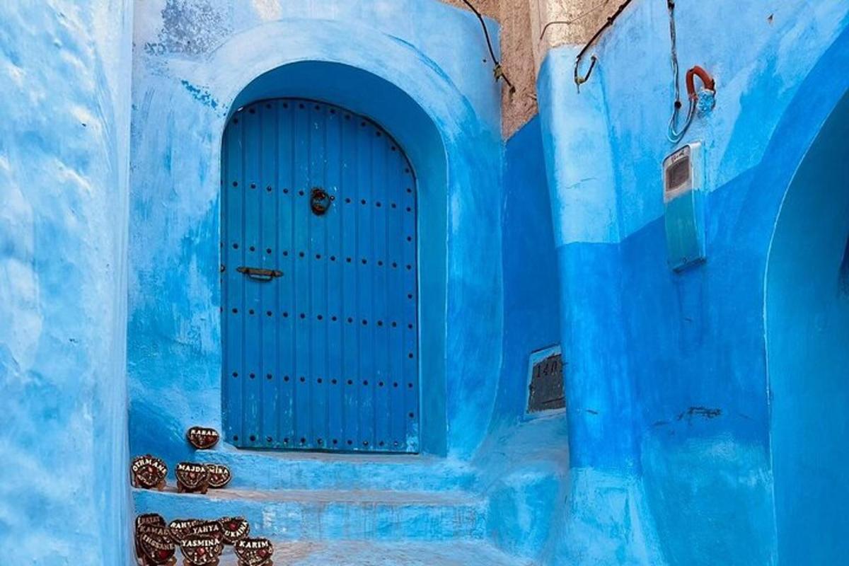 Un edificio azul con una puerta azul y algunas macetas.