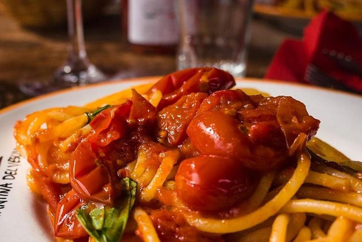 un piatto bianco di pasta con pomodori e formaggio