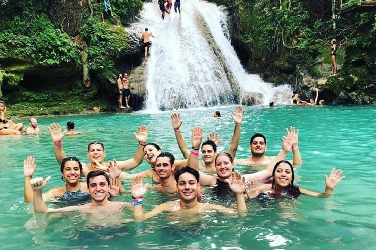 Un grupo de personas en el agua frente a una cascada.