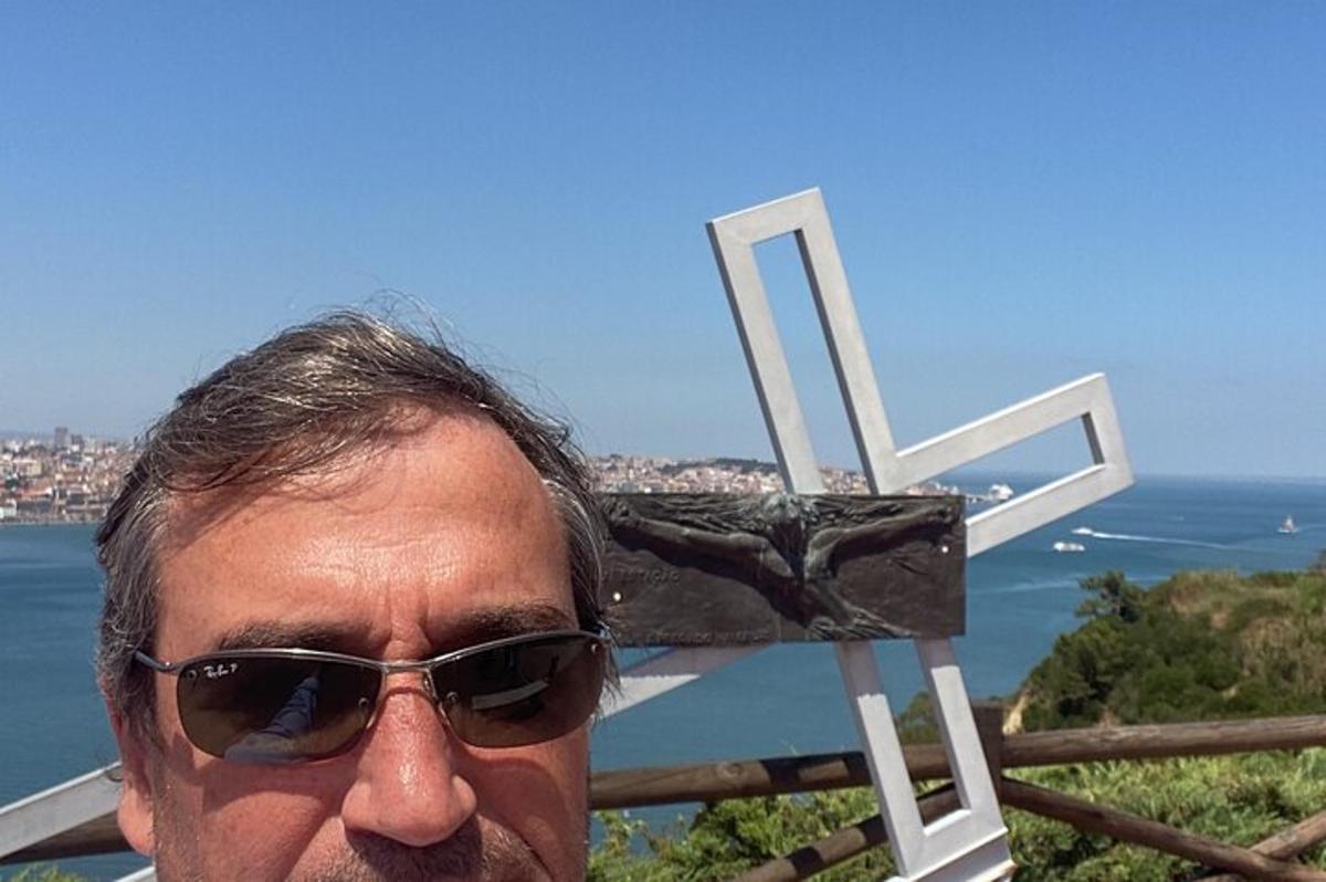 Ένας άντρας με γυαλιά ηλίου στέκεται δίπλα σε έναν σταυρό