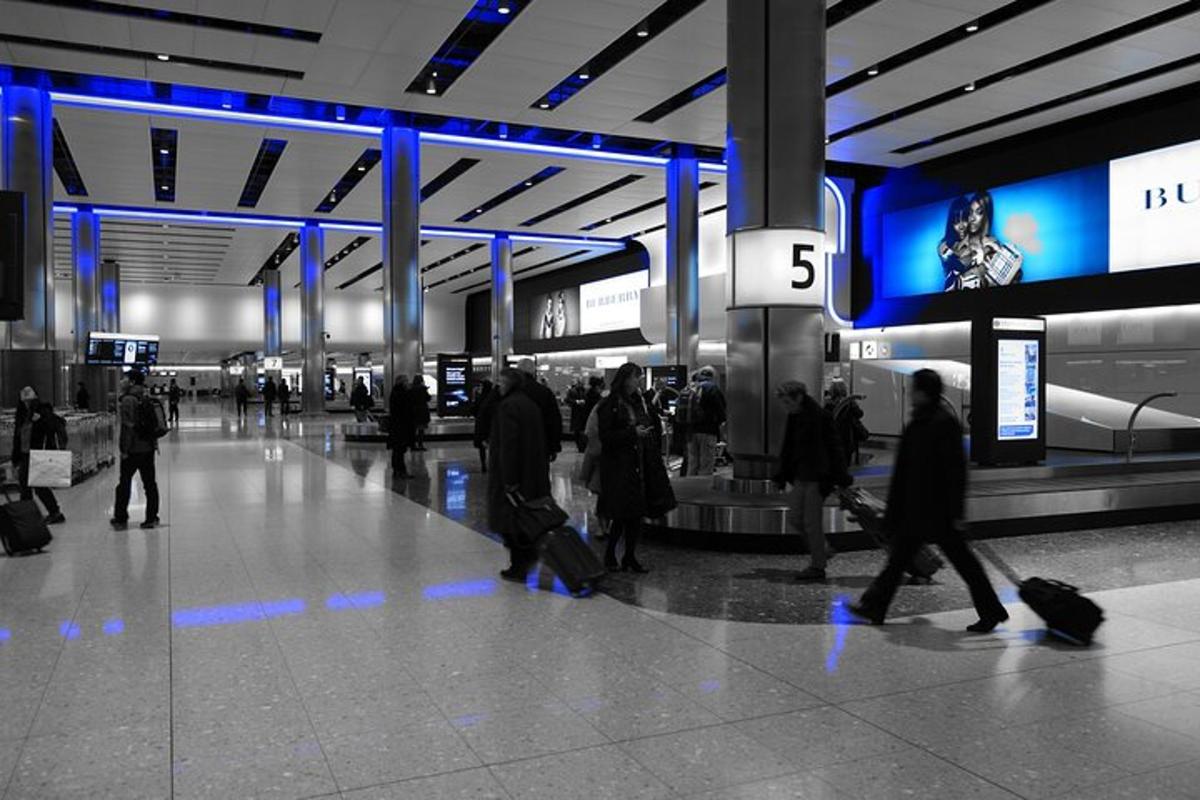 un grup de oameni care merg printr-un aeroport cu bagajele lor