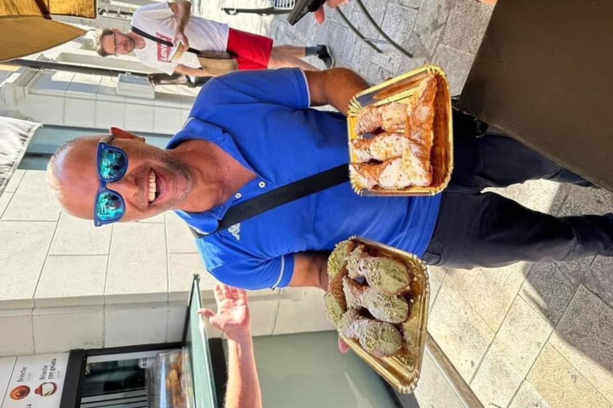 un uomo con occhiali da sole tiene in mano un vassoio di pasticcini