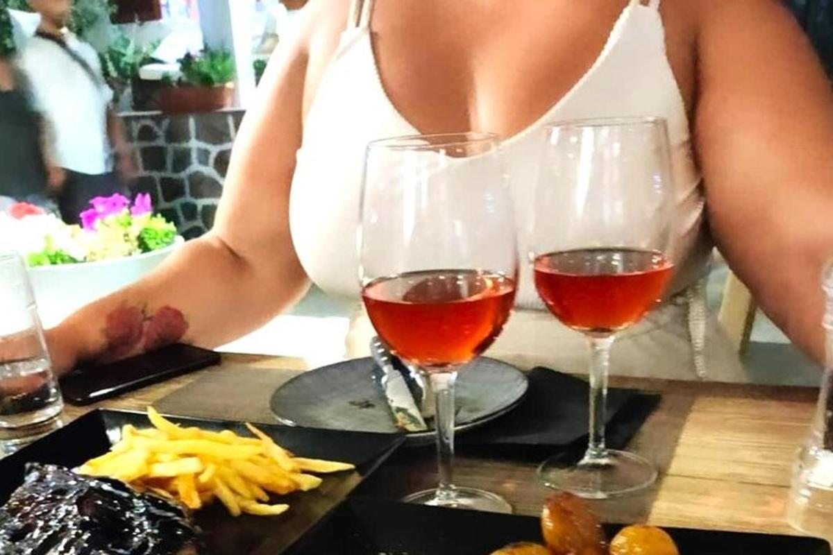 žena sediaca za stolom s dvoma pohármi vína