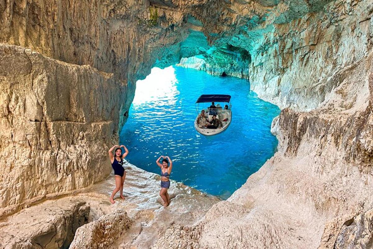 duas meninas em pé em uma caverna com um barco na água
