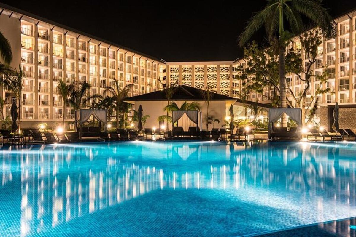 una grande piscina di fronte a un hotel di notte