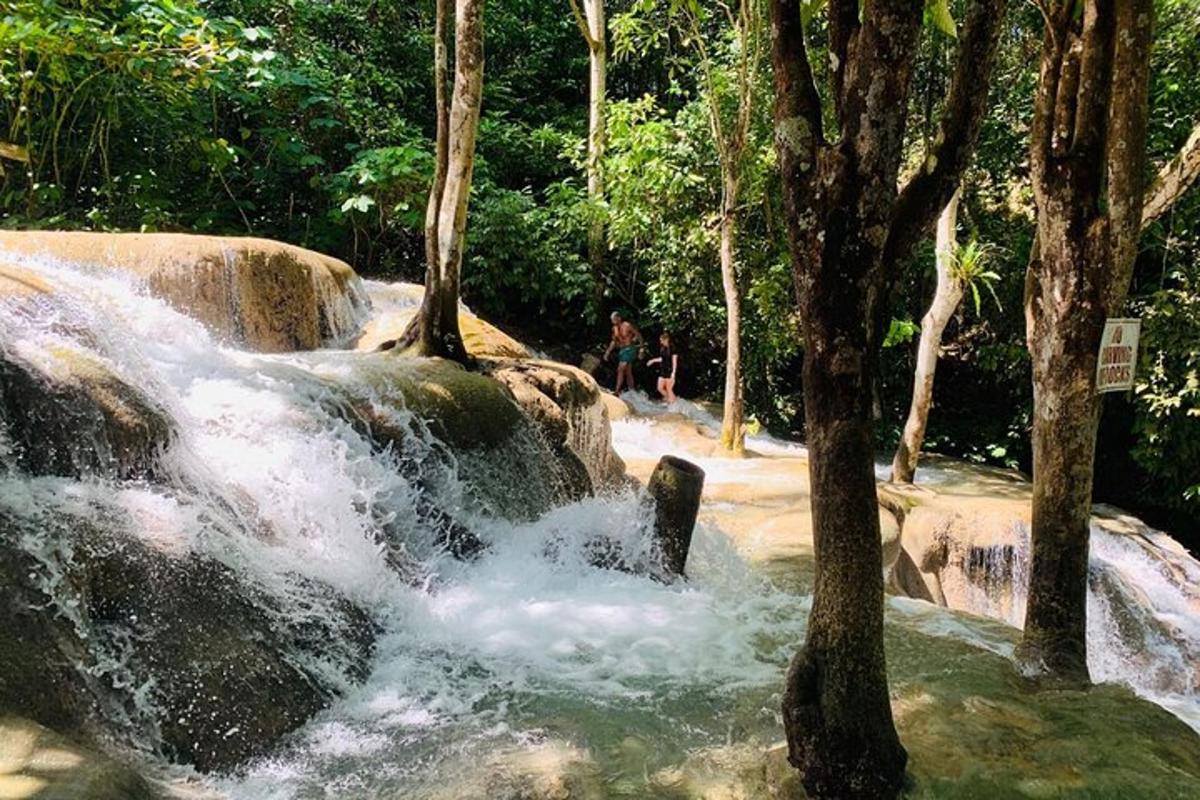 a waterfall in a park with people sitting on the rocks