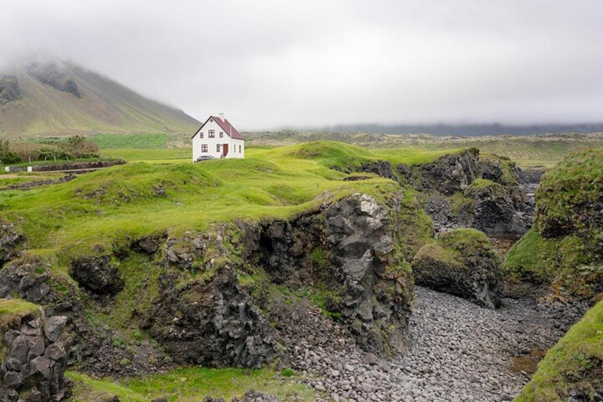 una piccola casa bianca su una collina coperta di muschio
