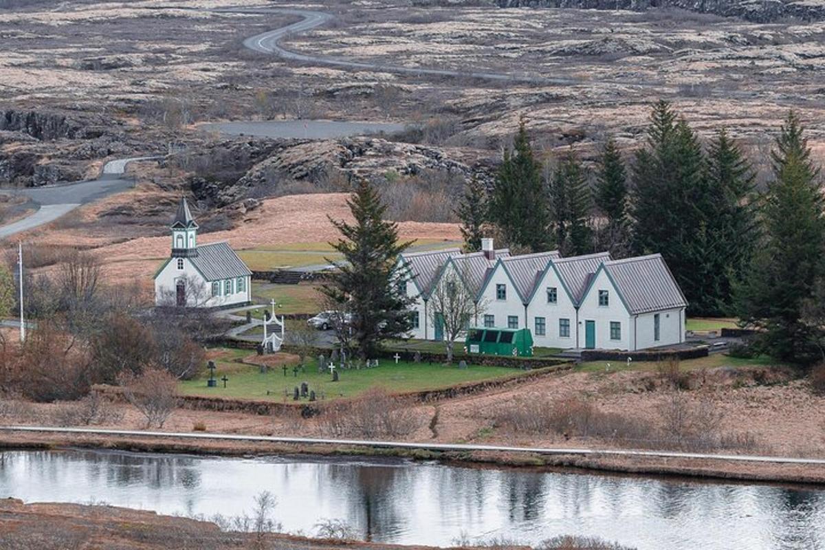 a large white house with a church next to a river