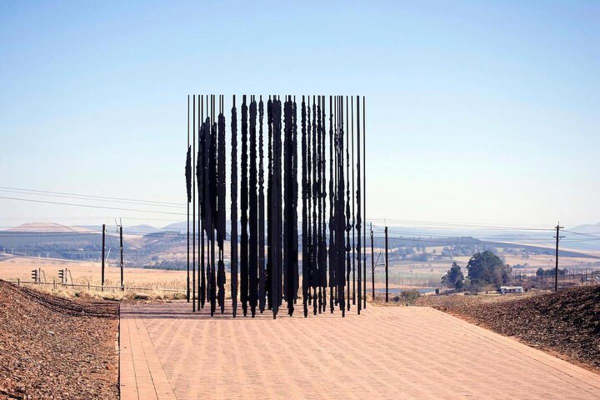 a sculpture of black poles on a dirt road