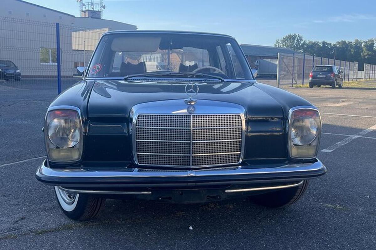 en gammel blå bil parkert på en parkeringsplass