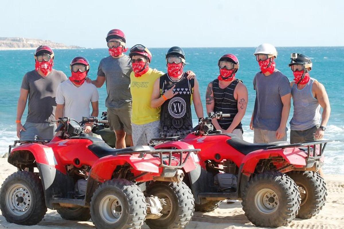 eine Gruppe von Menschen steht neben Geländefahrzeugen am Strand