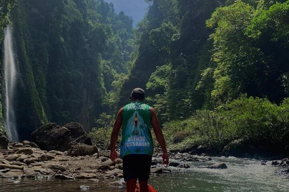 un uomo in piedi in un fiume che guarda una cascata