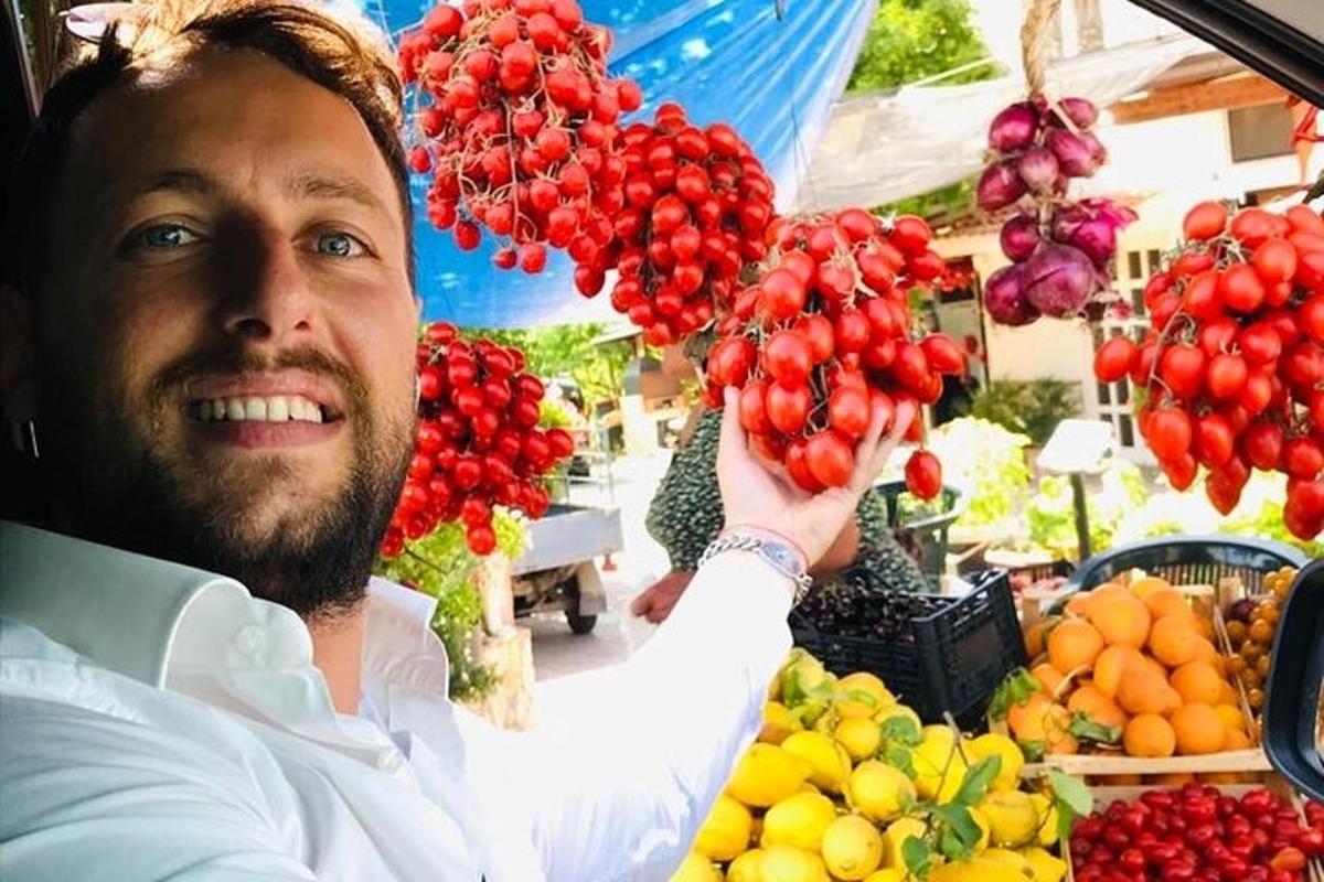 un bărbat care ține în mână o grămadă de fructe și legume
