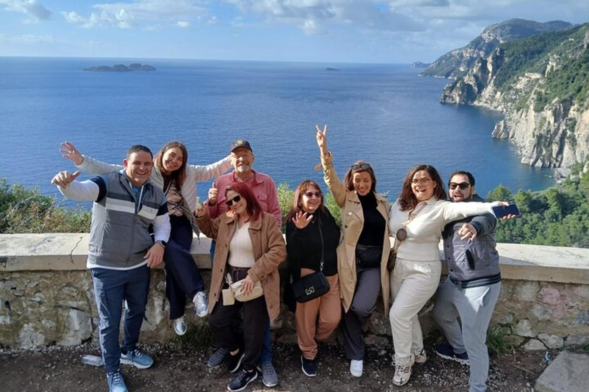 Un grupo de personas de pie en un muro cerca del océano.