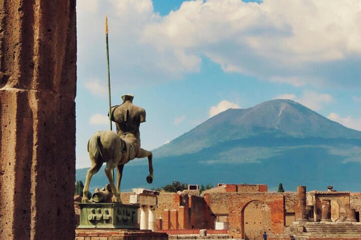 una statua in cima a un edificio con una montagna sullo sfondo
