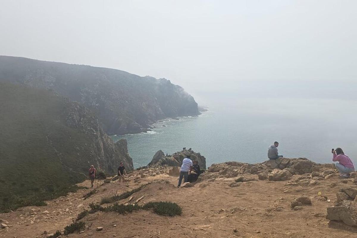 a group of people sitting on a hill near the ocean