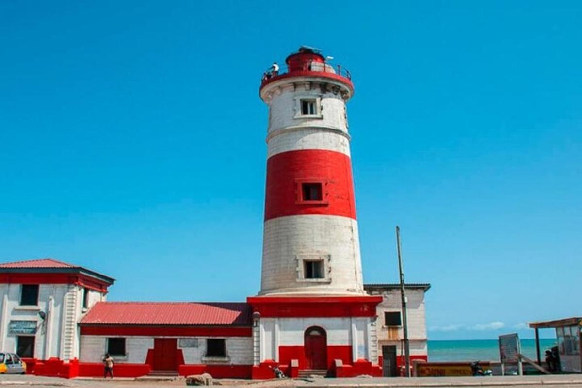 um farol vermelho e branco ao lado de um prédio