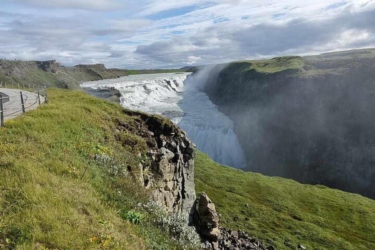 uma cachoeira na encosta de uma colina com um campo gramado