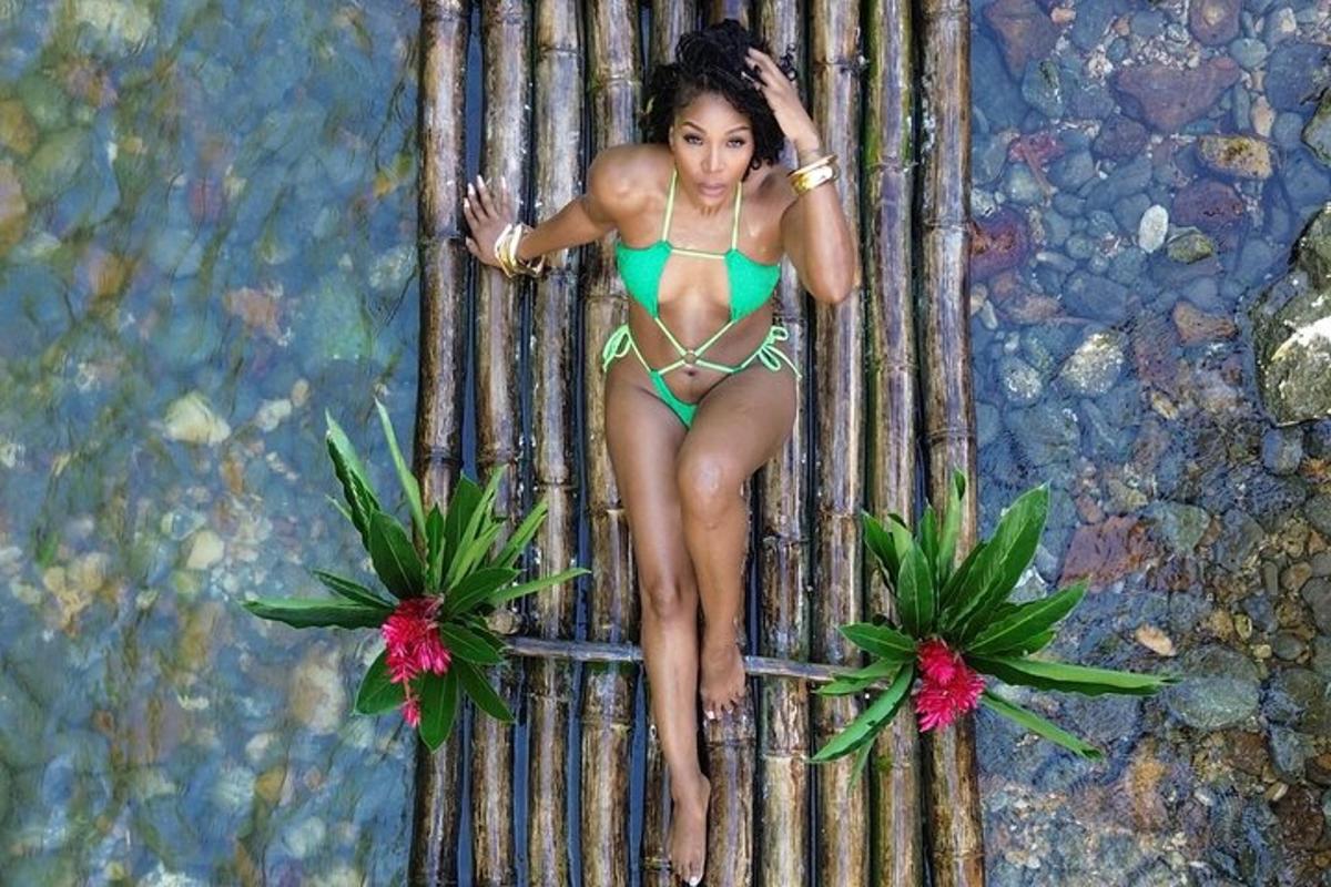 một người phụ nữ mặc bikini màu xanh lá cây đang ngồi trên bức tường tre