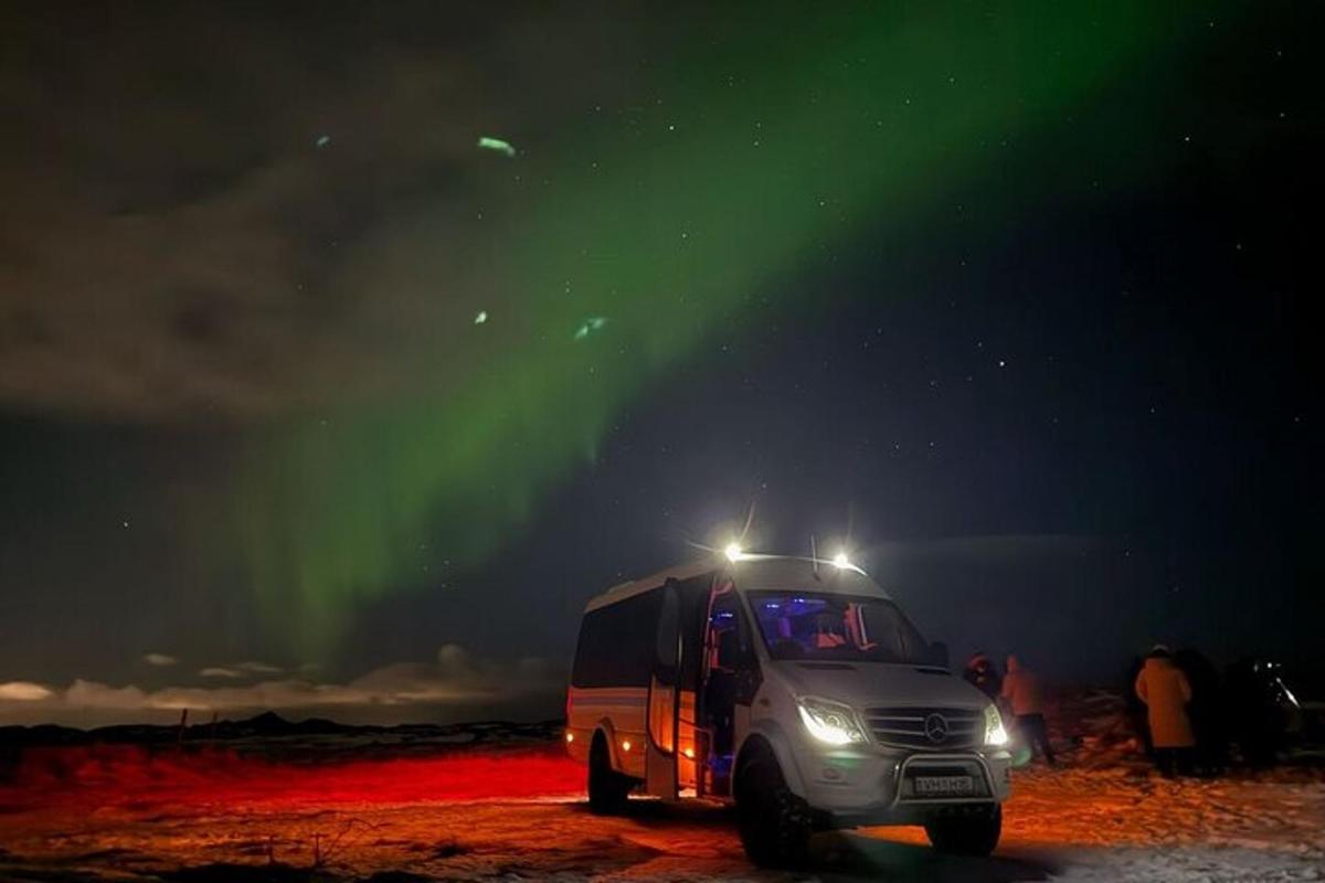 a semi truck parked under the aurora borealis