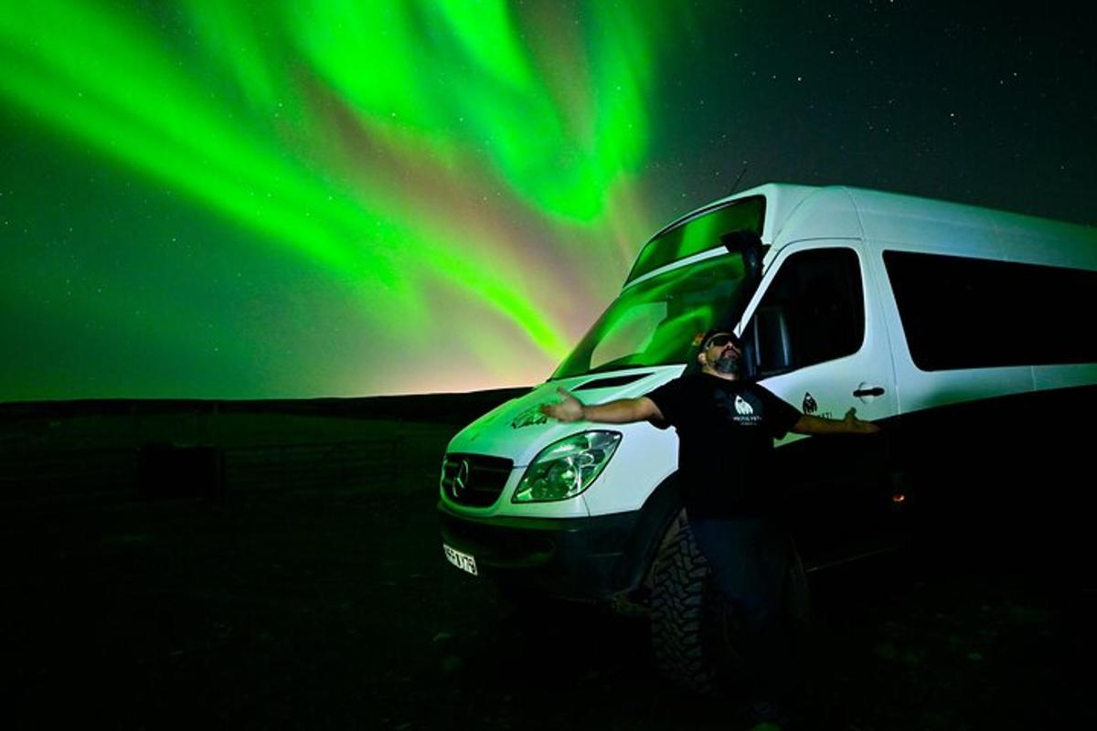 a man standing in front of a van under the aurora
