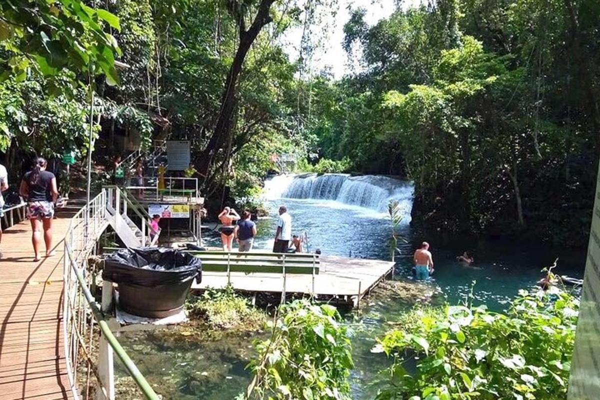 a group of people in the water near a waterfall
