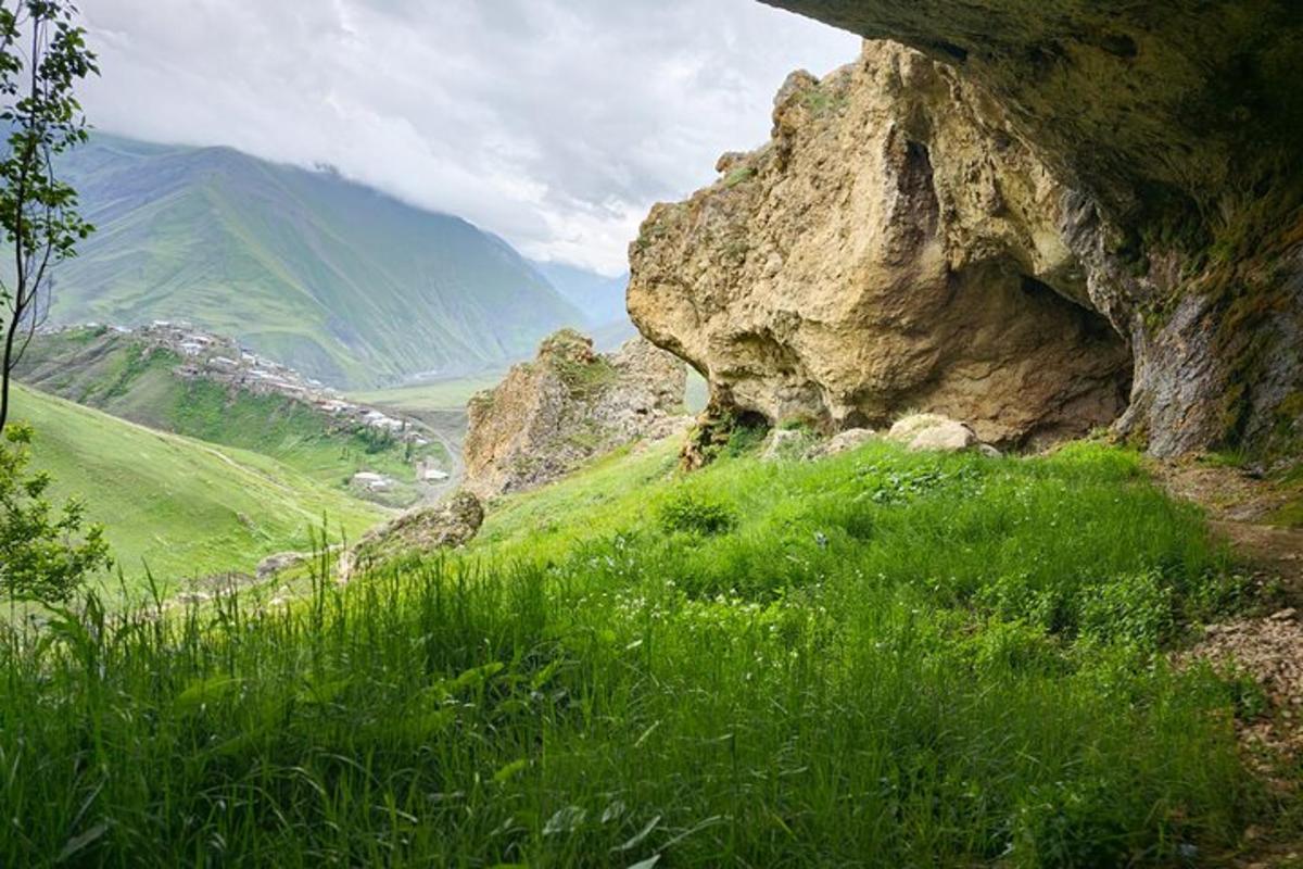 a large rock on a green hillside with grass