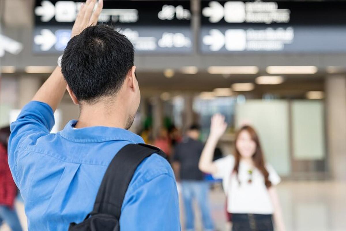 seorang pria dengan ransel memberi hormat kepada seorang wanita di bandara
