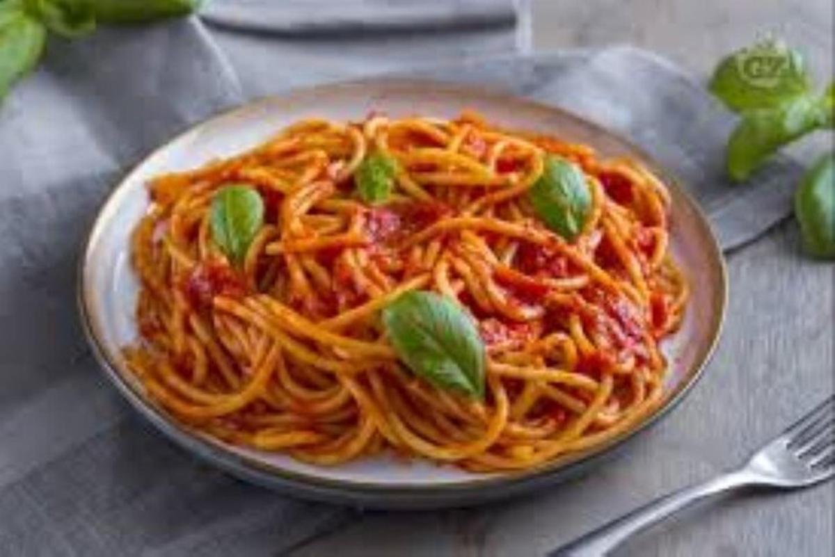 un piatto di spaghetti al basilico su un tavolo