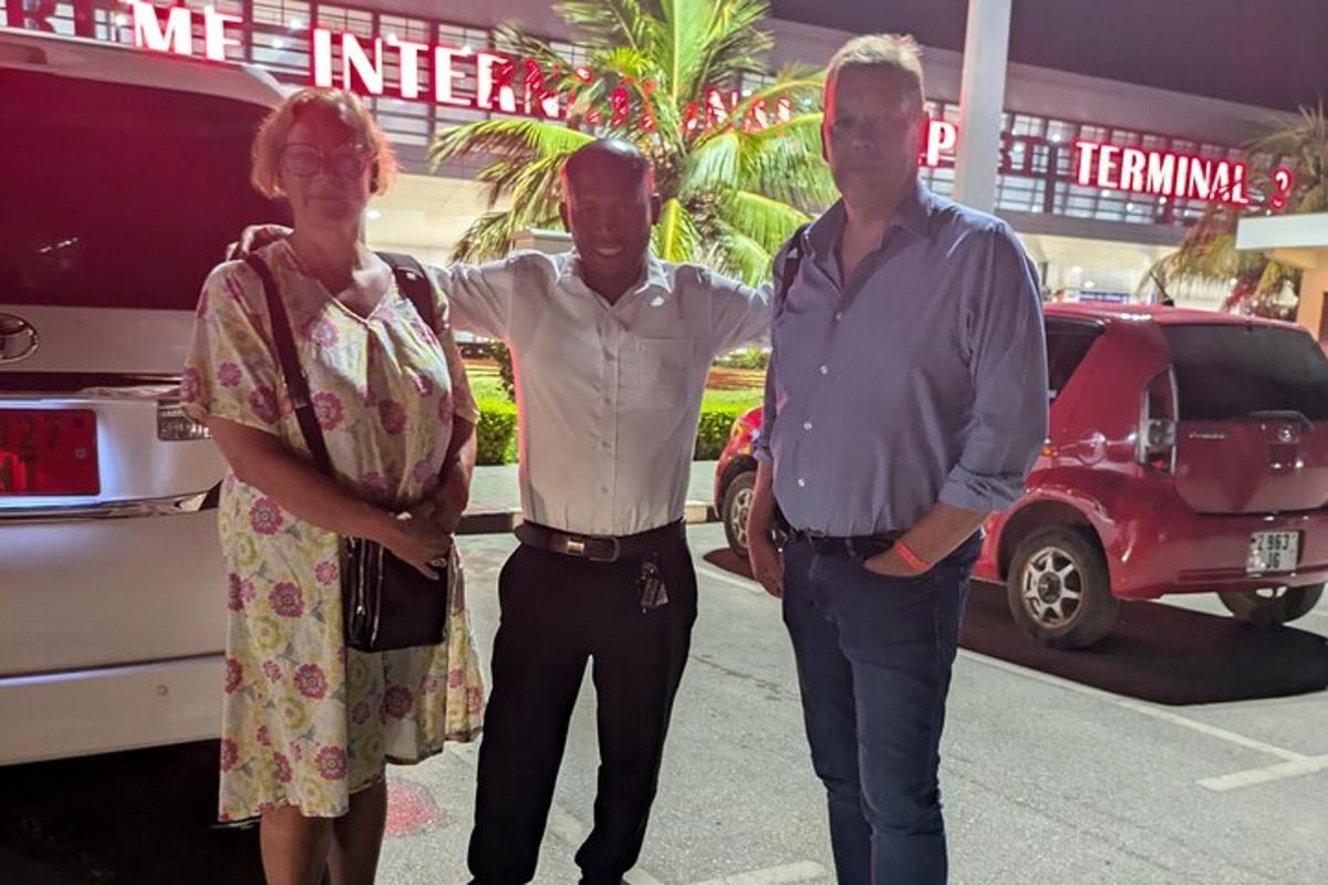 two men and a woman standing next to a car