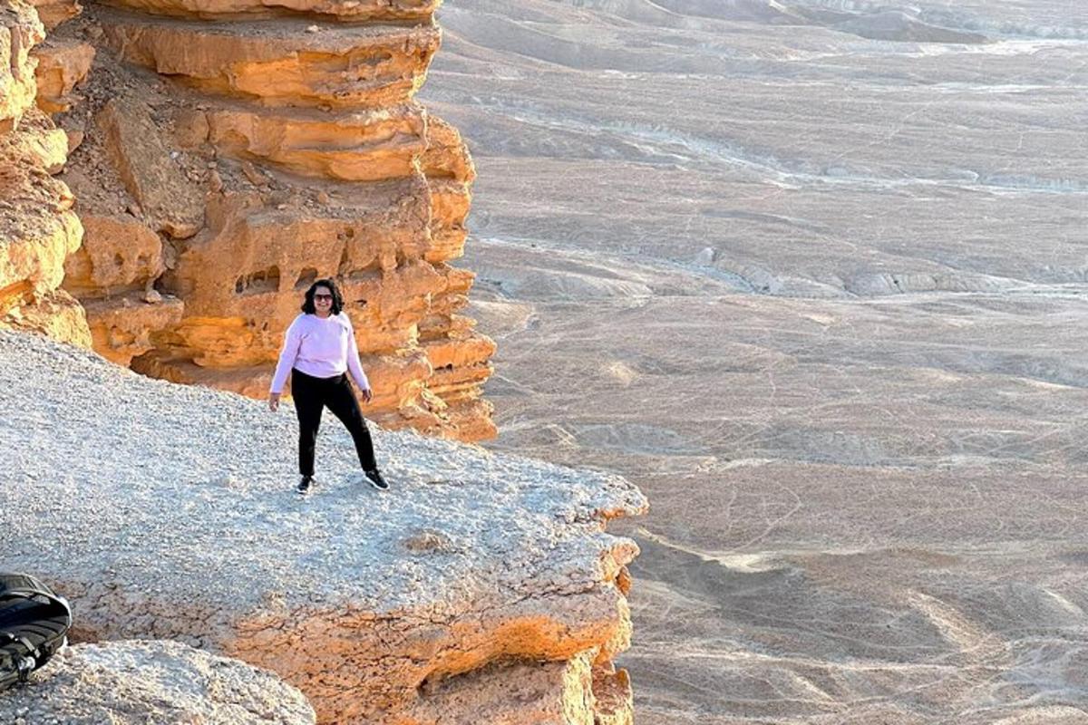 seorang wanita berdiri di atas tebing di padang pasir