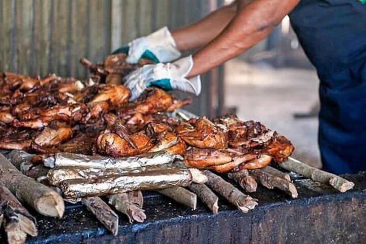 Ένας άντρας στέκεται δίπλα σε μια ψησταριά με ένα σωρό φαγητό