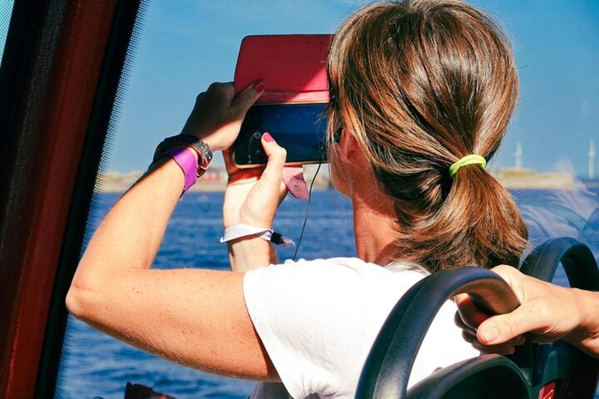 en kvinde tager et billede af havet med sin mobiltelefon